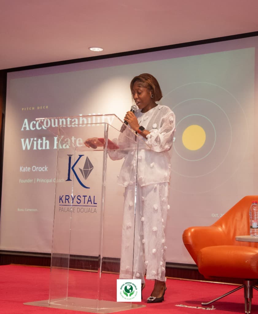 Kate Orock speaking on accountability from the podium at Krystal Palace, Douala